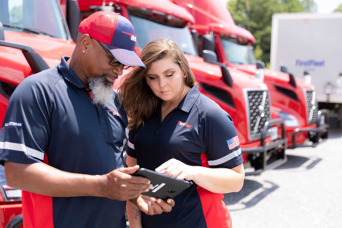 Two FirstFleet drivers talking while reviewing iPad screen