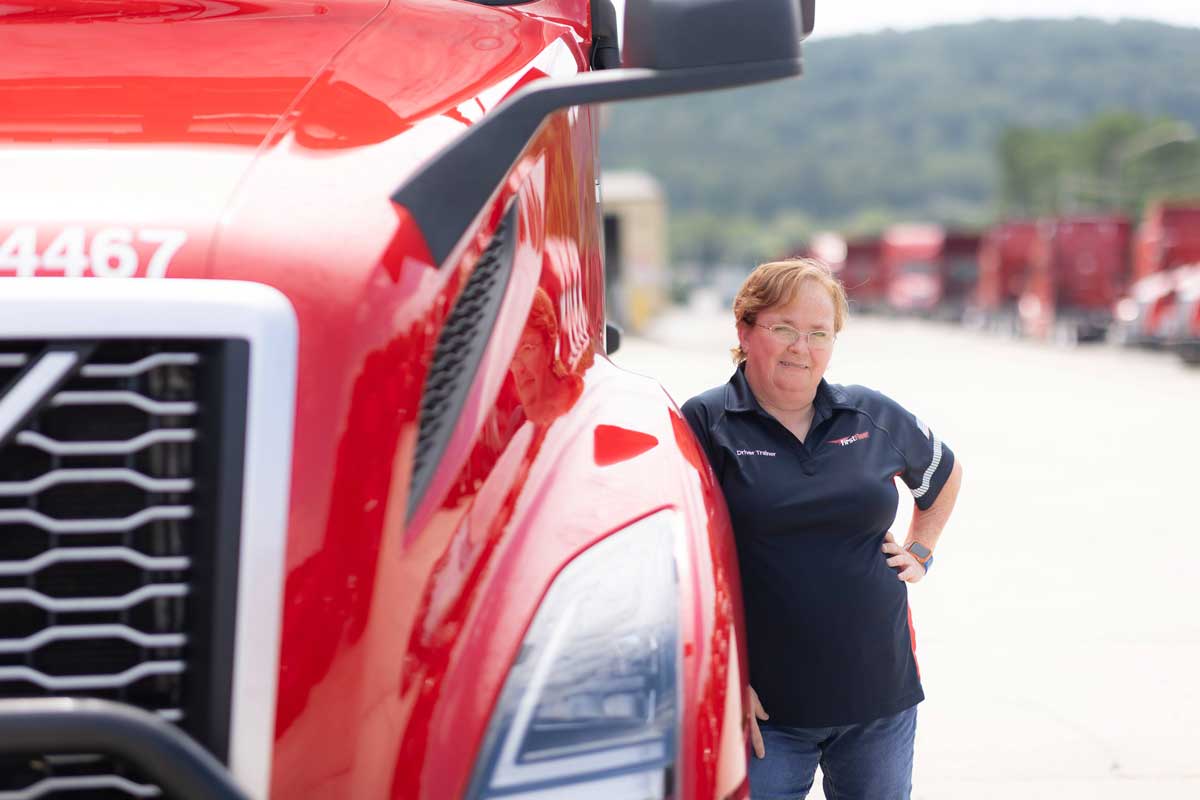 Female FirstFleet driver leaning against her truck