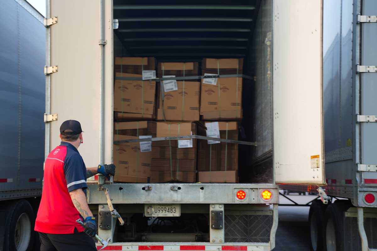 Driver opening doors to trailer loaded with stacks of new corrugated boxes