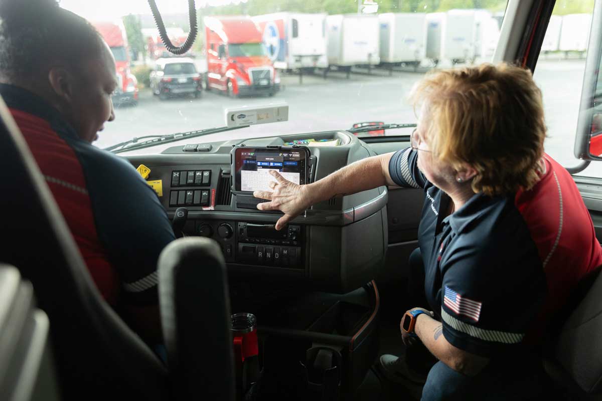 One female FirstFleet driver showing another how to use the in-cab tablet